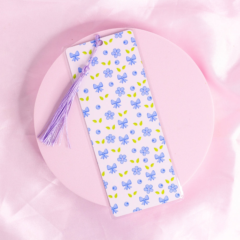 “Light floral bookmark with repeating pattern of blue bows, blueberries, and tiny pastel flowers – soft, sweet, and cottagecore-coded.”