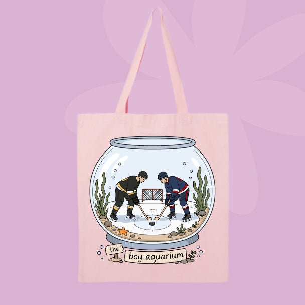 Pink canvas tote bag featuring two hockey players inside a fishbowl aquarium with the words the boy aquarium.