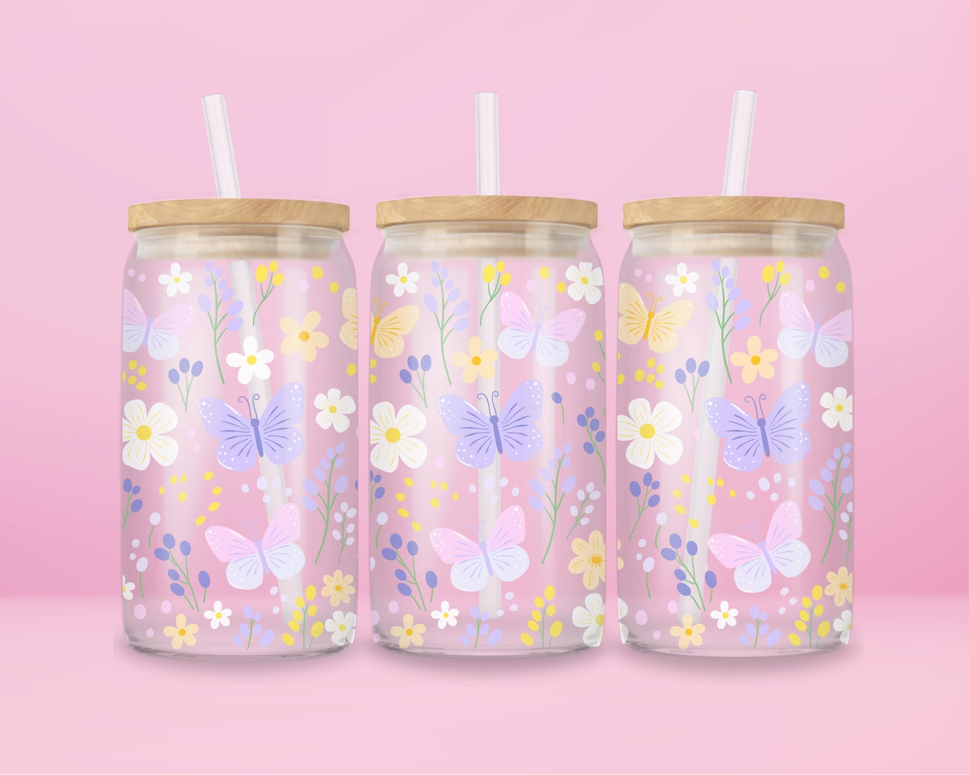 A pink glass cup decorated with pastel butterflies, daisies, and wildflowers in soft yellow, lilac, and white. A dreamy spring garden in glass form.