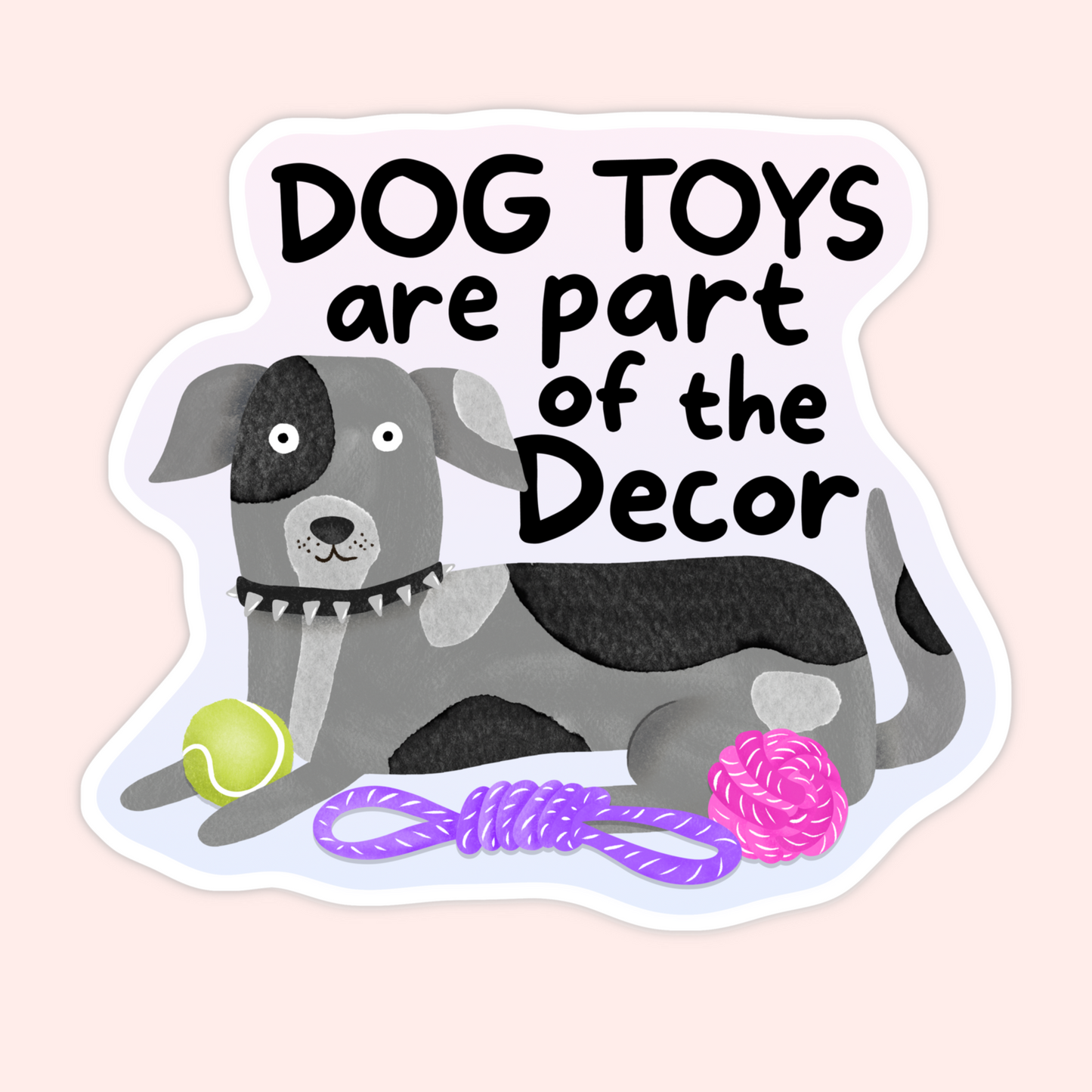 Gray and black dog lying with tennis ball and rope toys and text that reads “Dog toys are part of the decor.”