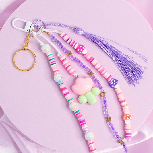Pink and purple mushroom keychain with floral charm, stripe beads, and lavender tassel.