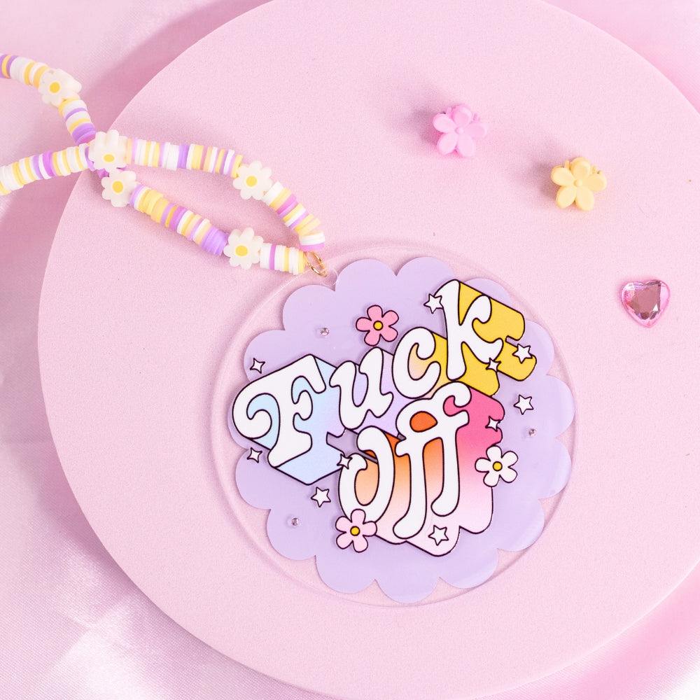 “Pastel purple and yellow ‘F*ck Off’ car charm with bold retro font and floral accents – sassy and unapologetic.”