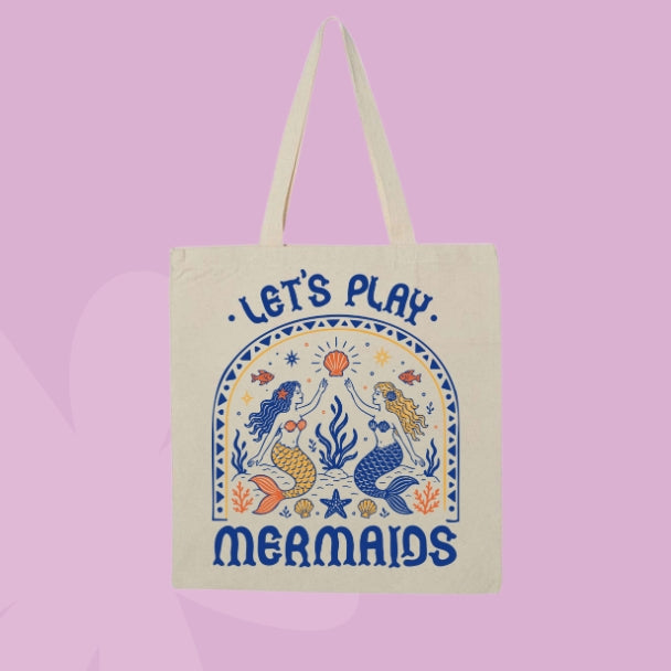 Beige canvas tote bag featuring retro-inspired mermaids, seashells, starfish, coral, fish, and the words Let’s Play Mermaids.