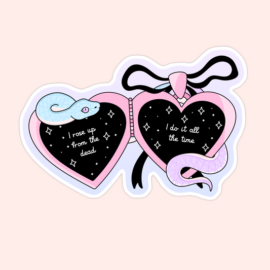 A pink and black heart-shaped locket sticker with a pastel snake and lyrics from Taylor Swift’s Look What You Made Me Do: “I rose up from the dead, I do it all the time.”