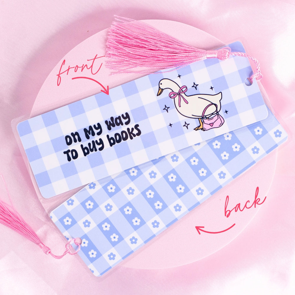 “Blue gingham bookmark featuring a goose carrying a pink purse with the quote ‘On my way to buy books’ – perfect for bookish adventurers.”