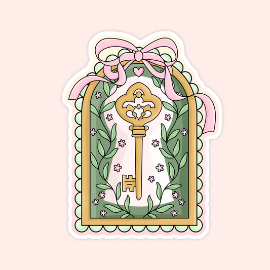 Sticker of a golden ornate key framed with green leaves, pink flowers, and a pink bow border.
