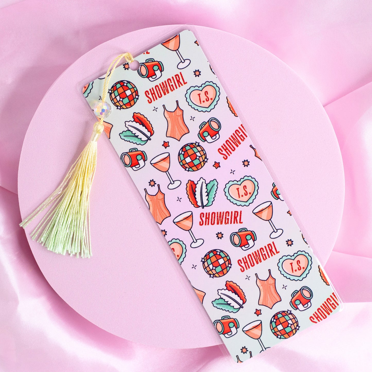 White bookmark with repeating disco balls, cocktails, corsets, and “Showgirl” text, finished with a pastel tassel.