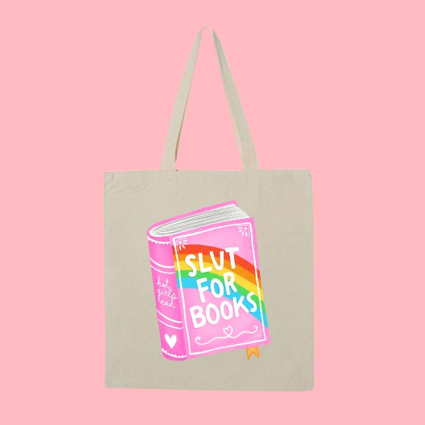 Beige tote bag with a colorful pink and rainbow book illustration that says “Slut for Books.”