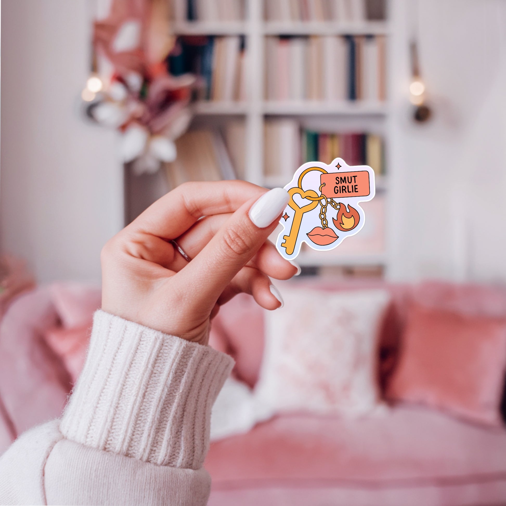 Bookish keychain sticker with a heart key, a “Smut Girlie” tag, a flame charm, and lips charm, designed in a playful pastel palette.