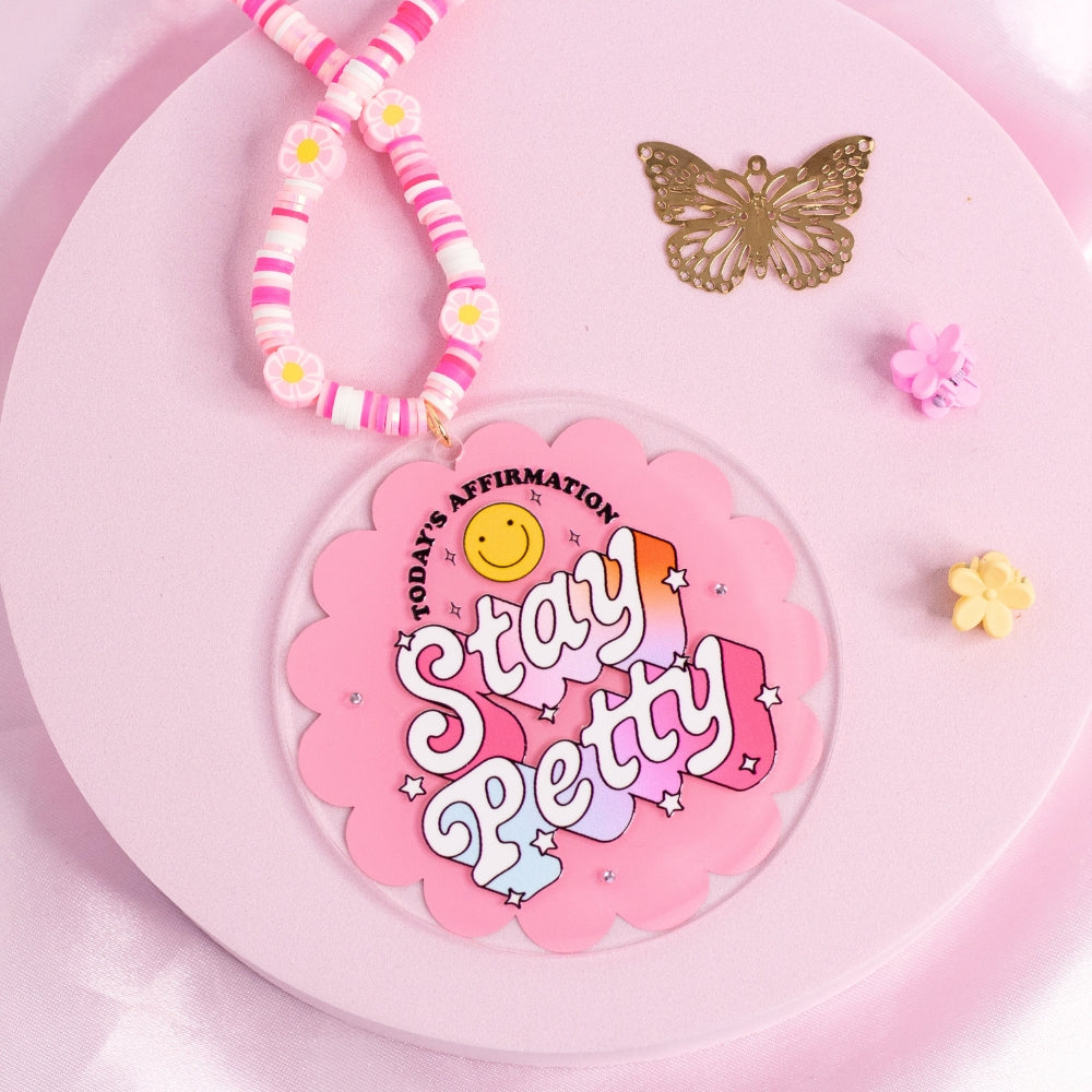 “Pink retro ‘Stay Petty’ car charm with positive (but spicy) affirmation and daisy beads – cute girly aesthetic.”
