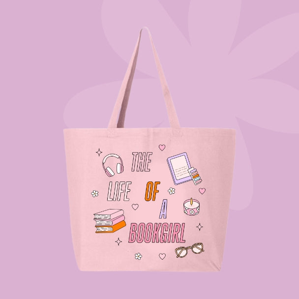 Pink tote bag with colorful pastel doodles of books, headphones, glasses, a candle, and text that says “The Life of a Bookgirl.”