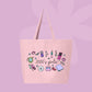 Large pink canvas tote bag featuring the words 2000’s girlie surrounded by Y2K icons including a flip phone, lip gloss, CD, butterfly clip, sneakers, mp3 player, and cute doodles.