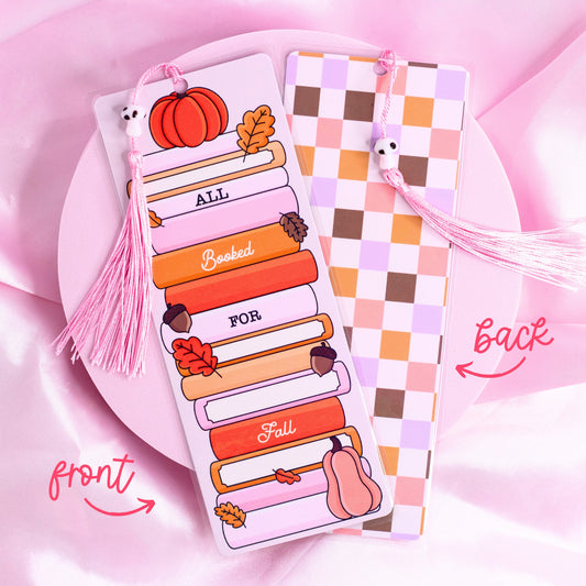 Fall-themed bookmark with stacked pastel books, pumpkin, leaves, and “All Booked for Fall” text, with checkered back design and pink tassel.