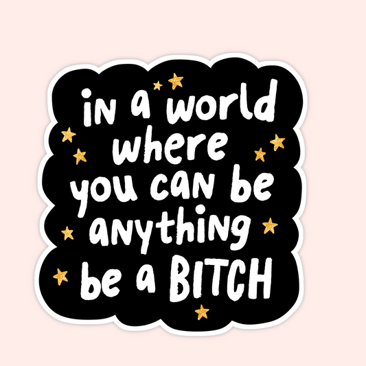 Black sticker with white lettering that says “in a world where you can be anything, be a bitch” surrounded by small gold stars.