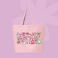 Large pink canvas tote bag featuring the words beach girlie surrounded by seashells, hibiscus flowers, palm trees, sea creatures, watermelon, and coastal doodles.