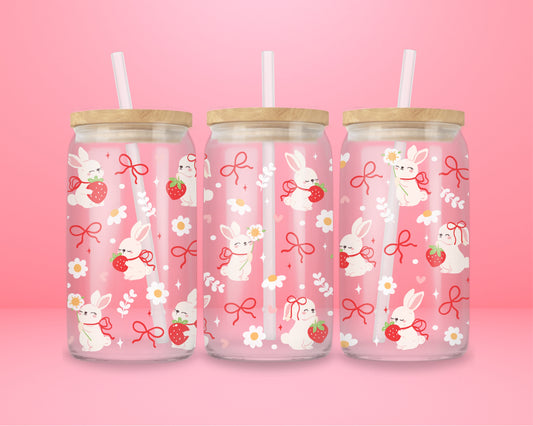 A sweet and soft glass cup covered in bunnies holding strawberries, red bows, white daisies, and hearts. Bunnycore perfection.