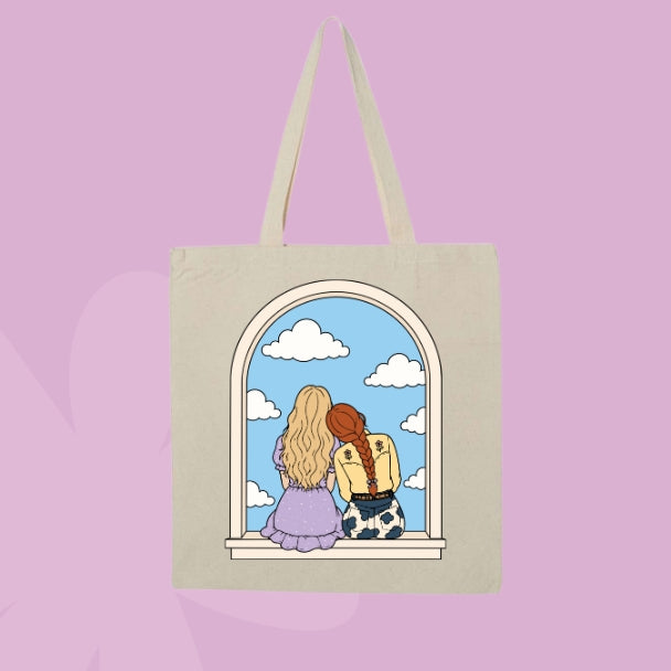 Beige canvas tote bag featuring two girls sitting together in an arched window with clouds and a blue sky.