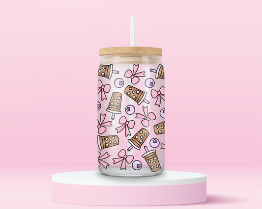 A pink glass cup with iced bubble tea, bows, and cute blueberries scattered all over. The ultimate pastel drink lover’s aesthetic.
