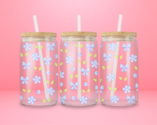 Glass cup featuring a repeating pattern of light blue bows, pastel blue flowers, blueberries, and green leaves on a pink background.