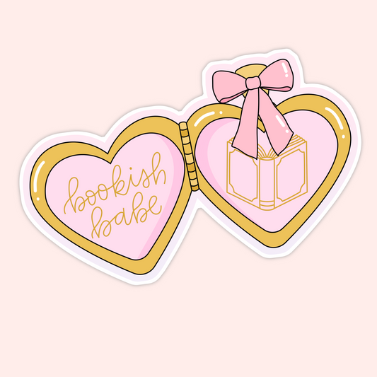 Heart-shaped pink and gold locket with a bow and an open book illustration and the phrase “bookish babe.”