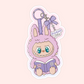 Cute purple Labubu monster holding a book with a bow keychain that says “The Readers” and “Bookish Girlie.”