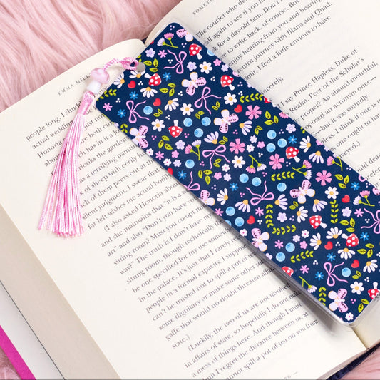 blue floral bookmark with bows and flowers placed inside an open book with pink tassel