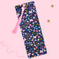blue floral bow bookmark with flowers mushrooms and pink tassel on pink background