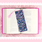 cute blue floral bookmark with bows and pink tassel on open book aesthetic pink background