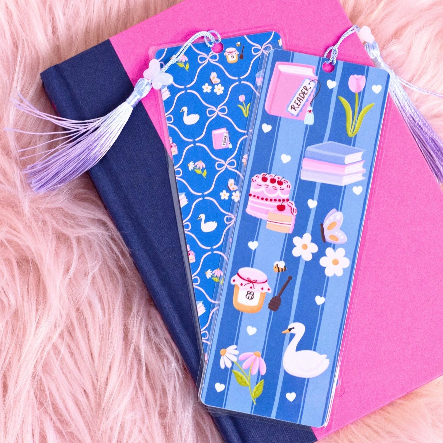 blue picnic bookmark with books cake flowers and swan design on stacked books with pink background