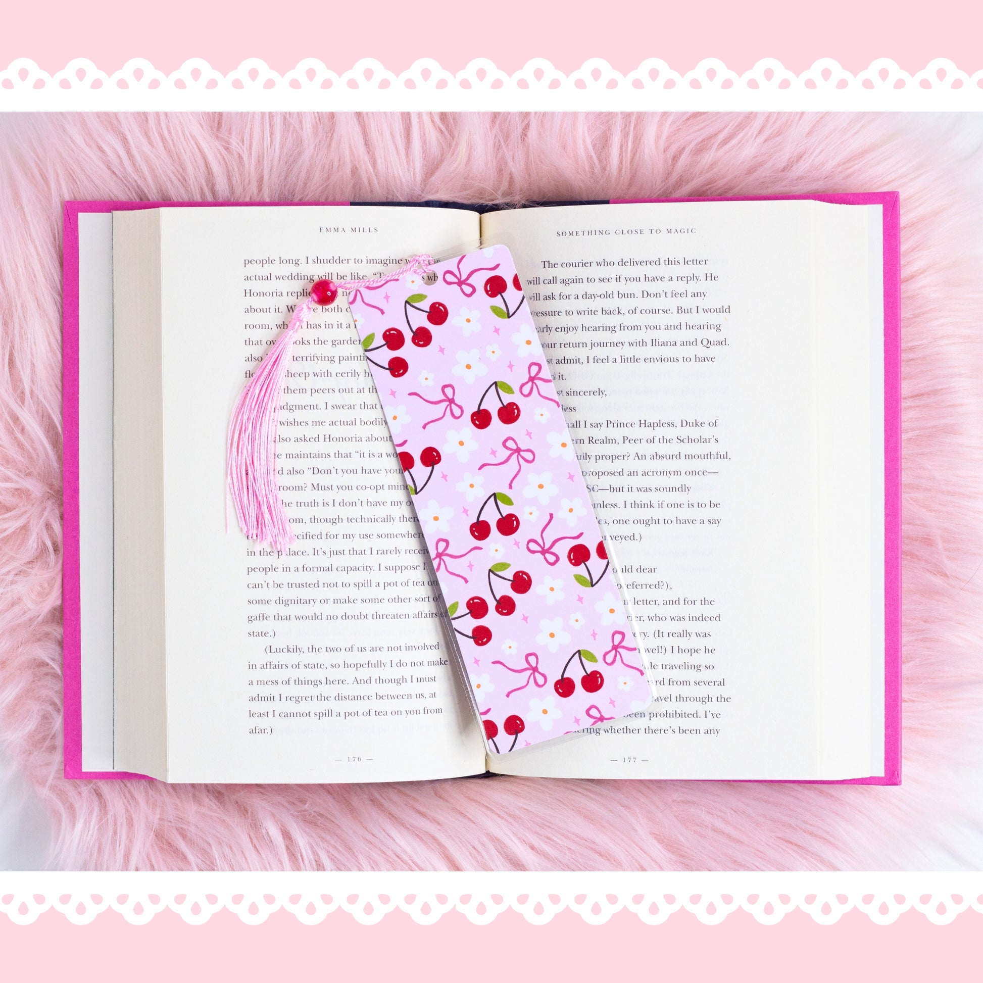 cherry coquette bookmark with bows and flowers placed on open book with pink aesthetic background