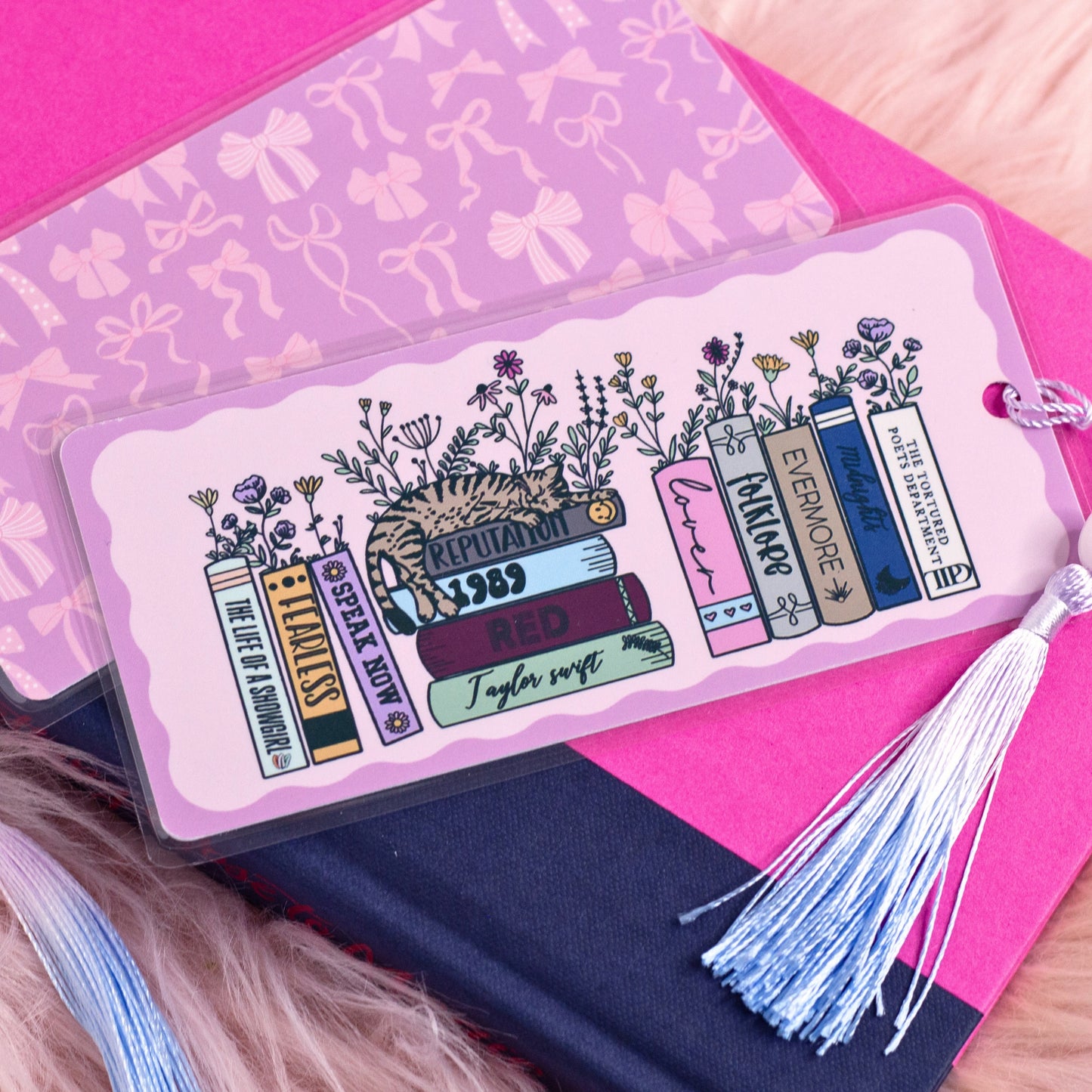 taylor swift eras inspired book stack bookmark with floral books and tassel styled on pink aesthetic background