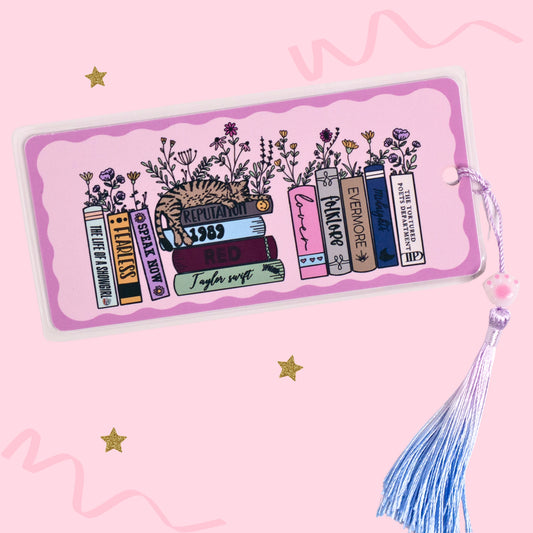 eras inspired book stack bookmark with illustrated books flowers and tassel on pink background