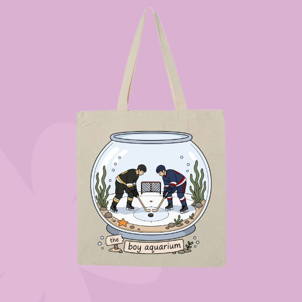 Beige canvas tote bag featuring two hockey players inside a fishbowl aquarium with the words the boy aquarium.