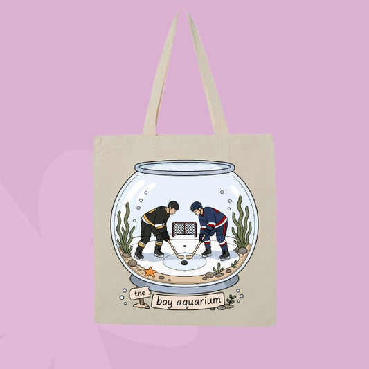 Beige canvas tote bag featuring two hockey players inside a fishbowl aquarium with the words the boy aquarium.