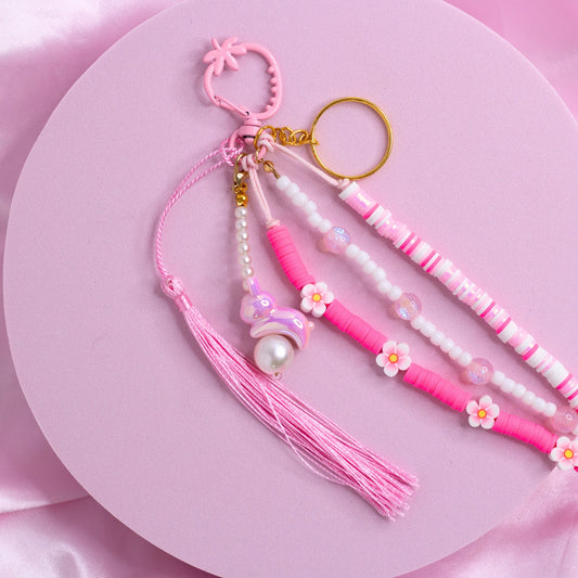 Pink purse charm with pearl and flower beads, sparkly accents, a pastel bunny charm, and tassel on a strawberry-shaped pink clasp.