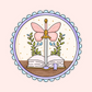 Open book with a sword topped with butterfly wings, framed with scalloped pastel border.