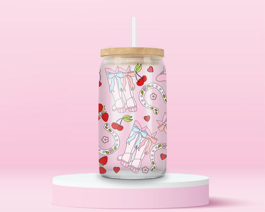 Pink glass can tumbler with cowgirl boots, bows, cherries, strawberries, and horseshoes in a coquette western pattern.