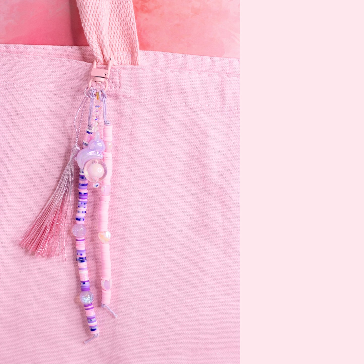 Pastel beaded purse charm keychain with pink tassel and iridescent glass bead clipped to a pink tote bag