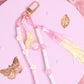 Close-up of daisy bunny purse charm keychain with pastel beads, gold clip, and pink tassel on pink aesthetic background