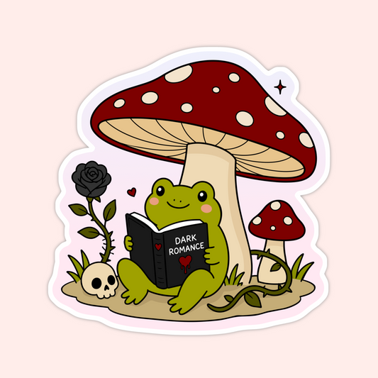 Cute frog sticker reading a dark romance book under a red mushroom with a black rose, skull, and vines.