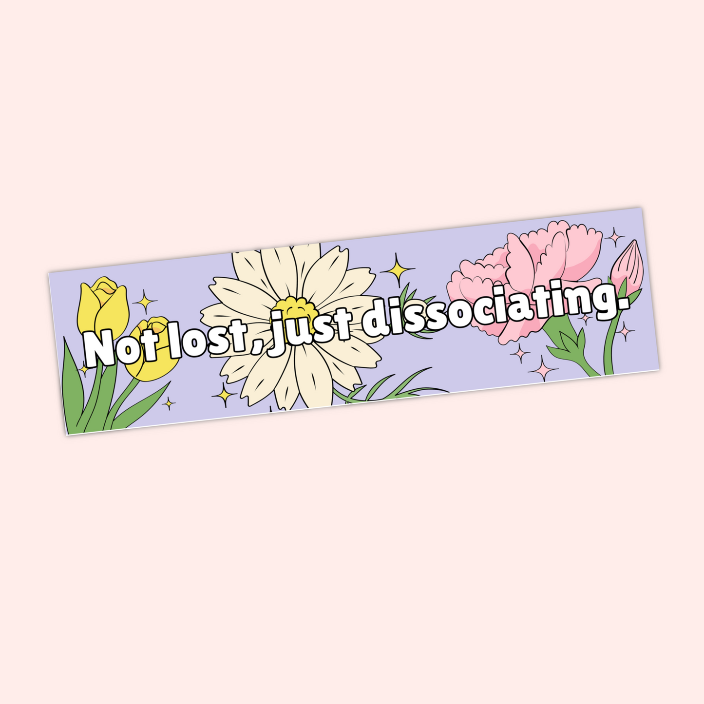 A hand holding a pastel purple bumper sticker that reads "Not lost, just dissociating" with illustrated flowers and sparkles.