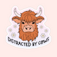 Cute vinyl sticker featuring a fluffy highland cow surrounded by daisies with the phrase “Distracted by Cows.”