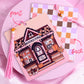 Double-sided bookmark with a pink fall bookstore illustration on the front and pastel checkered pattern on the back, with a mushroom bead tassel.