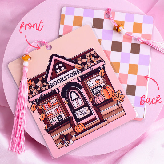Double-sided bookmark with a pink fall bookstore illustration on the front and pastel checkered pattern on the back, with a mushroom bead tassel.