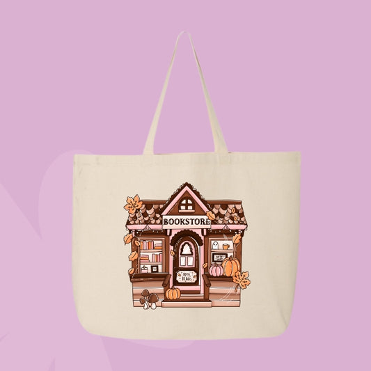 Beige tote bag with a cozy autumn bookstore illustration decorated with pumpkins, books, and fall leaves.