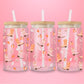 Pink glass tumbler with illustrations of fall boots decorated with stars and bows, pumpkins, and autumn leaves.