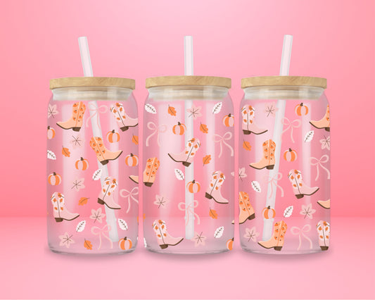 Pink glass tumbler with illustrations of fall boots decorated with stars and bows, pumpkins, and autumn leaves.