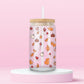 glass tumbler with scattered mini illustrations of pumpkins, mushrooms, and autumn leaves, with bamboo lid and straw.