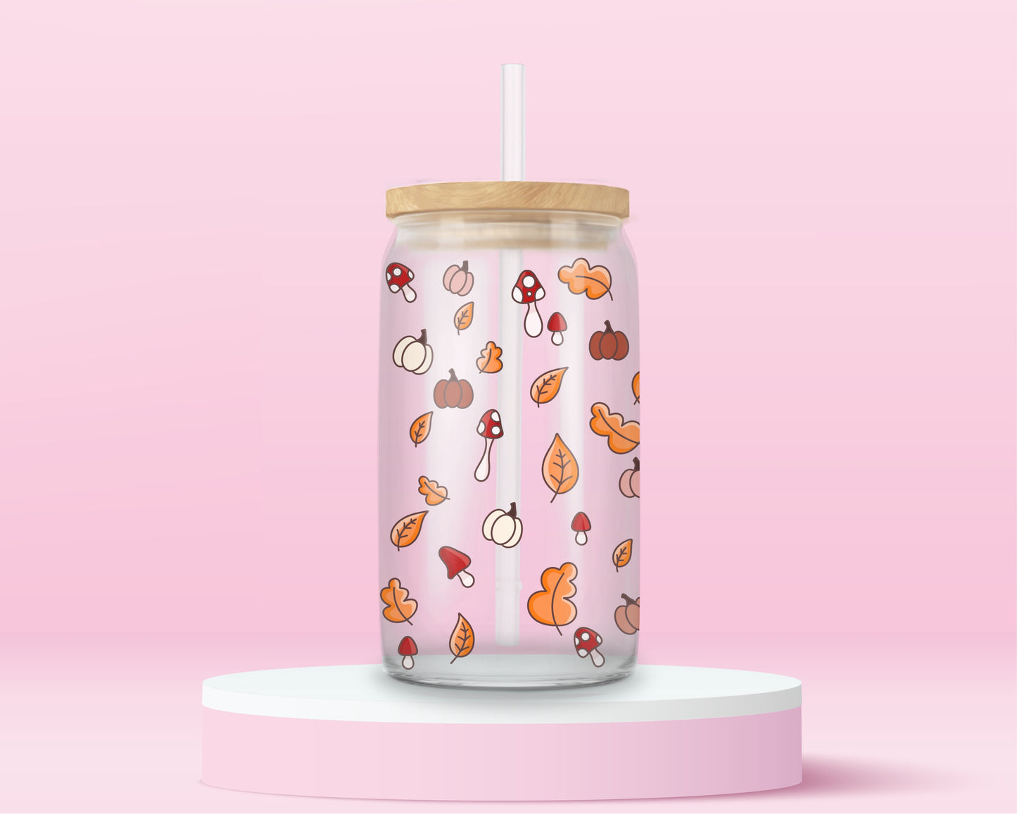 glass tumbler with scattered mini illustrations of pumpkins, mushrooms, and autumn leaves, with bamboo lid and straw.