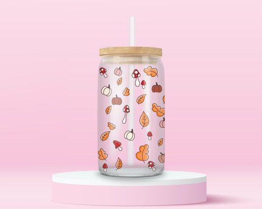 glass tumbler with scattered mini illustrations of pumpkins, mushrooms, and autumn leaves, with bamboo lid and straw.